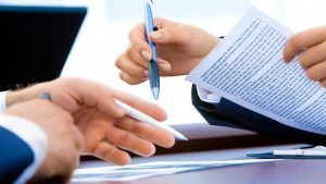 como funciona a partilha da herança - Foco na mão de duas pessoas assinando um contrato.