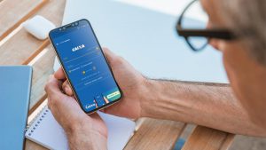Imagem de um homem segurando um smartphone, cuja tela apresenta o aplicativo da Caixa Econômica Federal.