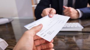Um homem entregando um cheque cruzado a outra pessoa