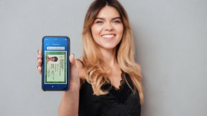 Garota sorrindo e segurando o celular com a tela virada para a frente e com o aplicativo do RG Digital aberto.