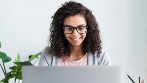 Imagem de uma mulher sorridente olhando para um notebook, como se estivesse solicitando a segunda via da conta Celpa pela internet.