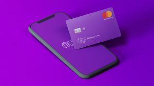 Foto de um celular aberto no aplicativo do Nubank e ao lado um cartão de crédito Nubank para negativado.