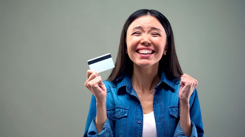 Foto de uma jovem sorridente comemorando a conquista de um cartão de crédito com limite de R$ 3 mil.