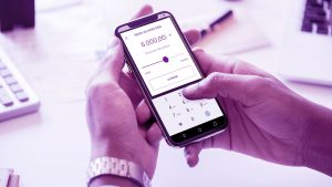Mão de um homem segurando um celular. Na tela do celular o aplicativo Nubank.