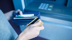 Adulto de frente para um caixa eletrônico para pagar a taxa de adiantamento a depositante
