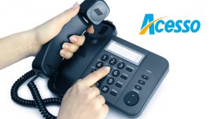 Imagem com fundo banco e a mão de um adulto discando no telefone o número da Acesso Card