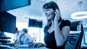 Mulher sorrindo, com um headseat telemarketing, representando uma atendente do Banco Cetelem.
