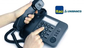 Mão de uma pessoa digitando um número em um telefone. Ao lado o Logotipo do Itaú.