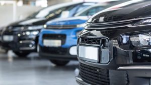 Como funciona seguro auto para carro blindado - Imagem com três carros, dois pretos e um azul, com foco no capô e placa deles.