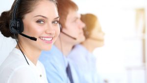 Imagem de uma mulher sorrindo para a câmera, com um headset de telemarketing, representando uma atendente da Getnet.