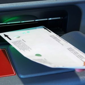 Pessoa inserindo um envelope em um caixa eletrônico, como se estivesse fazendo um depósito.