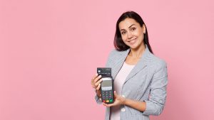 Mulher sorridente, com um blazer cinza, segurando uma maquininha de cartão sem mensalidade.