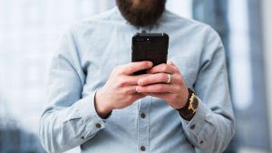 Foto de um homem segurando um celular para fazer uma transferência.