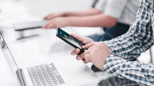 Foto de uma mulher segurando um celular para realizar uma transferência para o Banco Sicoob utilizando o código do banco.