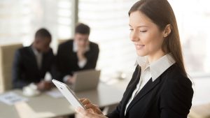 Imagem de uma mulher de terno olhando para um tablet, como se estivesse fazendo um DOC.