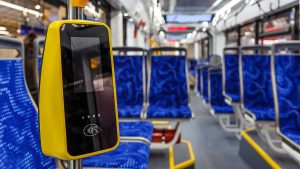 Foto do interior de um ônibus de transporte coletivo. Uma catraca com aparelho que reconhece cartão.