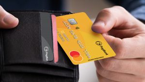 Imagem com foco na mão de um homem segurando uma carteira preta e puxando o cartão de crédito PagSeguro.