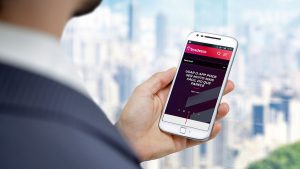 Imagem de um homem de terno olhando para um celular, cuja tela mostra o aplicativo do Banco Bradesco.