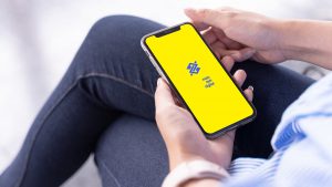 Imagem de uma pessoa segurando um celular, cuja tela mostra o aplicativo do Banco do Brasil.