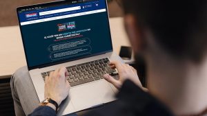 Foto de um homem branco usando um notebook. O aparelho está ligado no site das casas Bahia, em que o homem está fazendo a solicitação do crediário digital.