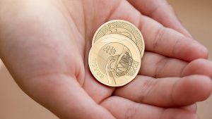 Foto de uma mão segurando duas moedas das Olimpíadas de 2016.