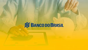 Homem mexendo em uma calculadora e colocando moedas em um cofre de poupança. No centro da imagem está localizado o logotipo do Banco do Brasil.