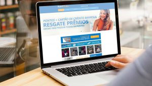 Foto de uma pessoa usando um notebook. Na tela o site do programa BanriClube.