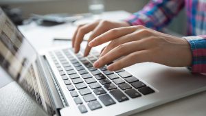 Imagem de uma mulher mexendo em um notebook, como se estivesse fazendo o login no site da Cemig.