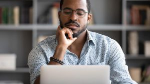 Foto de um homem negro usando um notebook para renegociar suas dívidas no site do Grupo Recovery.