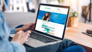 Foto de uma mulher utilizando um notebook, cuja tela apresenta o site oficial da Caixa Econômica Federal - Título de Capitalização.