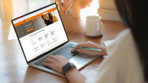 Imagem de uma mulher mexendo em um notebook, cuja tela apresenta a plataforma Itaú Bankline.