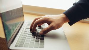 Imagem de uma mão sobre o teclado de um notebook, como se estivesse procurando na internet o passo a passo de como emitir a segunda via Equatorial.